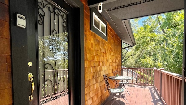 A wooden deck with a black door, a small table, and chairs.