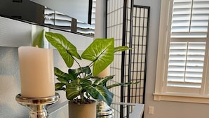A modern kitchen with a stainless steel range hood, a potted plant, and a candle on a silver pedestal.