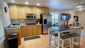 A modern kitchen with wooden cabinets, stainless steel appliances, and a central island with bar stools.