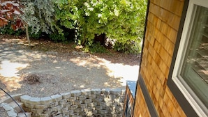A wooden staircase leading to a house with a stone wall and a wooden fence.