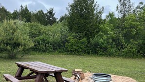 Ett picknickbord på en gräsyta, med en sandlåda och en metallring.