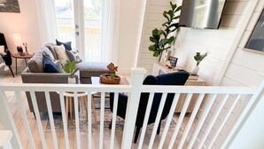 Un interior moderno con una escalera, una sala de estar con sofá y mesa de centro, y un comedor con sillas y mesa.