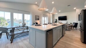 Una cocina moderna con una isla grande, iluminación colgante y vistas a una piscina.