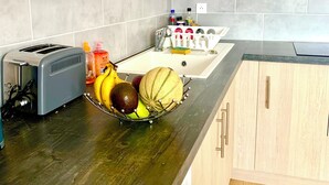 Una cocina con armarios de madera, un tostador, un lavabo y un frutero sobre la encimera.