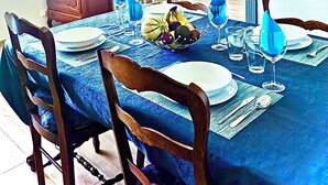 Un comedor con mantel azul, sillas de madera y un televisor en la pared.