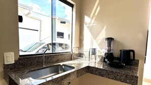 A kitchen with a granite countertop, a sink, a window, and a coffee maker.