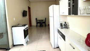 A compact kitchen with a gas stove, a refrigerator, and a dining area with a table and chairs.