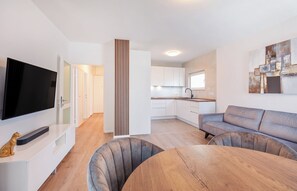 Un salon moderne avec un téléviseur à écran plat, un canapé et une table à manger.