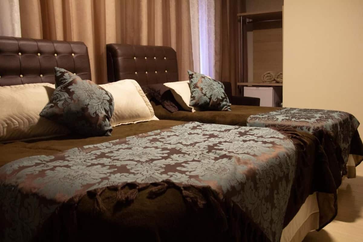 A hotel room with two beds, each with a patterned bedspread and matching pillows.