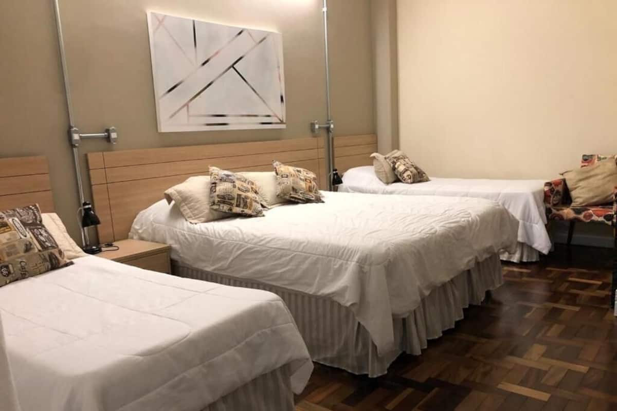 A hotel room with two beds, a wooden headboard, a wall-mounted artwork, and a patterned rug.