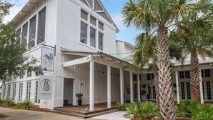 A white building with a covered porch and palm trees. - Worth the Coast Beach House-Golf Cart, Pool, In-law suite, resort community+more (Port St. Joe)