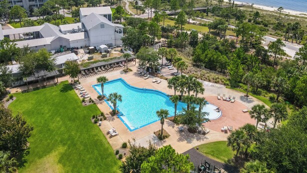 An aerial view of a resort with a large swimming pool, a beach, and a building with a modern design. - Worth the Coast Beach House-Golf Cart, Pool, In-law suite, resort community+more (Port St. Joe)