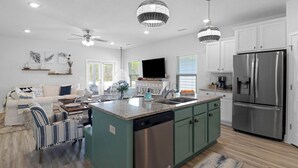 A modern kitchen with a central island, stainless steel appliances, and teal cabinetry. - Worth the Coast Beach House-Golf Cart, Pool, In-law suite, resort community+more (Port St. Joe)