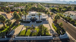 Un hotel grande y moderno con fachada simétrica, varias secciones y un patio central con palmeras.