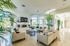 Un salón amplio con chimenea, asientos cómodos y ventanas grandes.
