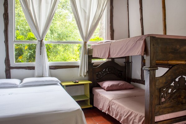 A rustic bedroom with a bunk bed, a bedside table, and a window with curtains.