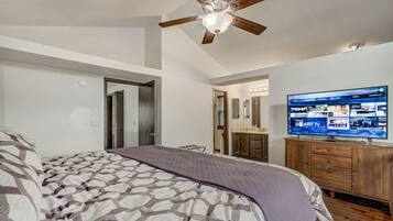 A bedroom with a bed, a ceiling fan, a TV, and a wooden dresser.