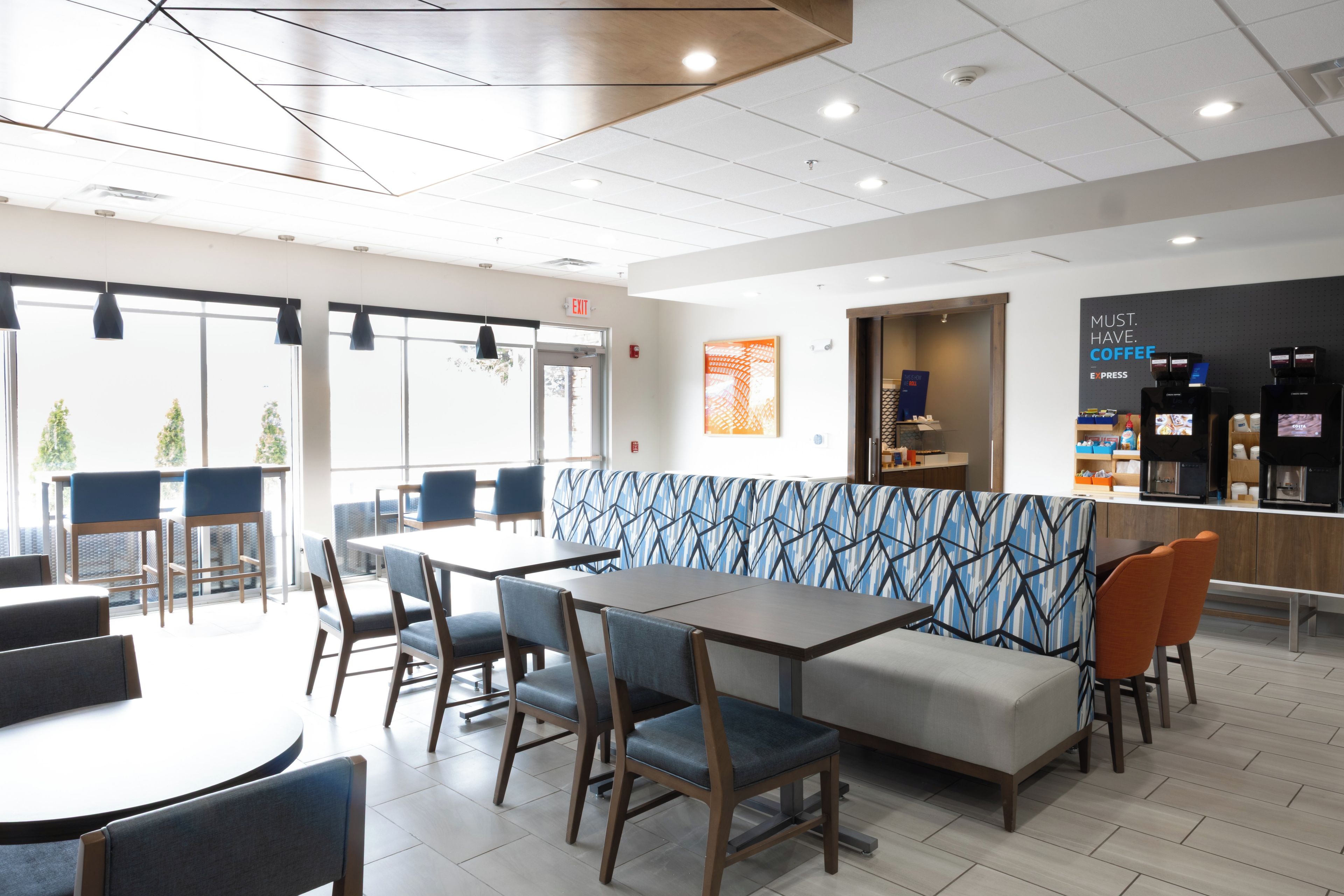 A modern cafe interior with seating arrangements, including tables and a patterned sofa.