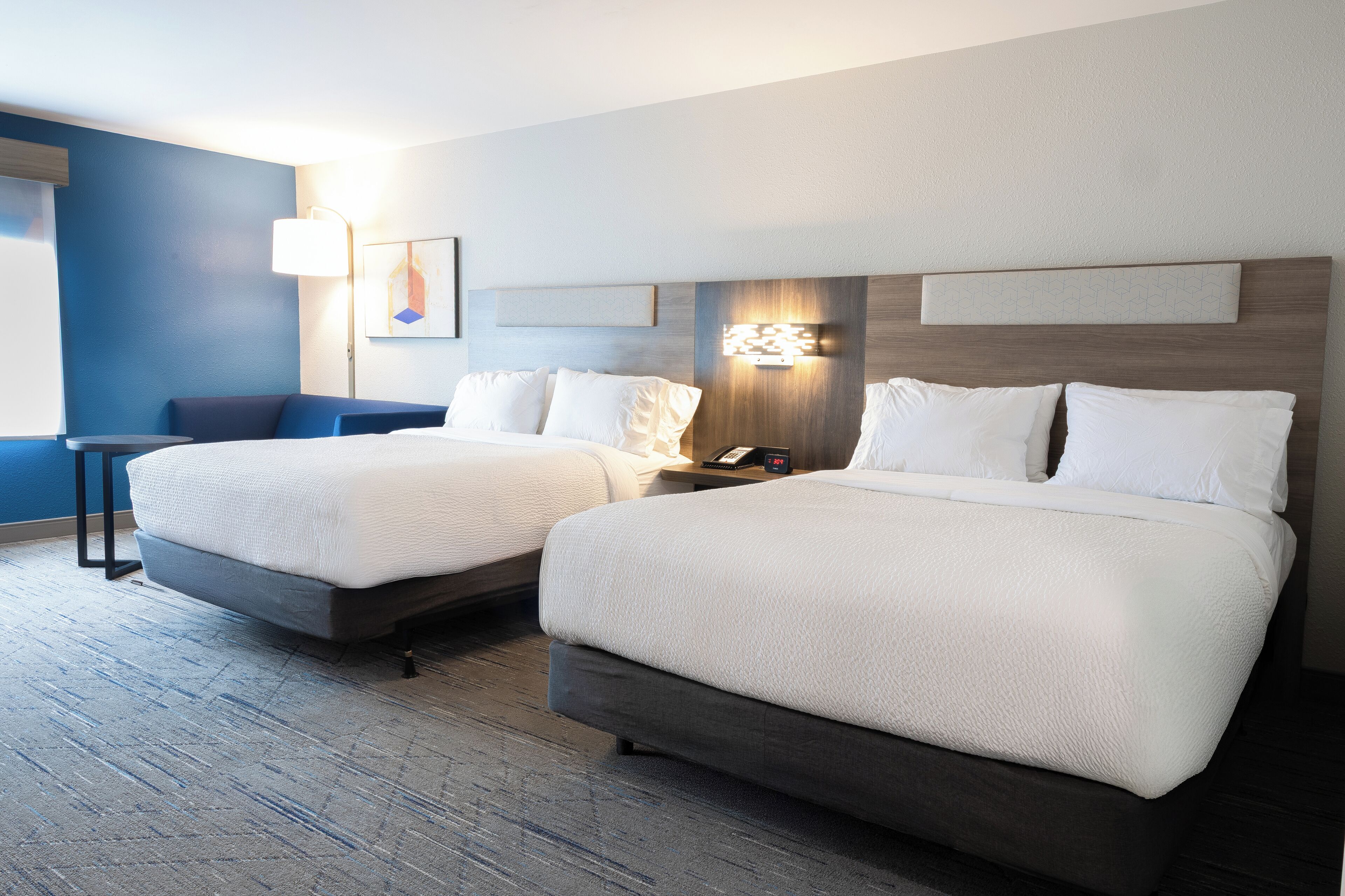 A hotel room with two beds, a desk, and a chair.