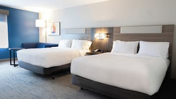 A hotel room with two beds, a desk, and a chair.