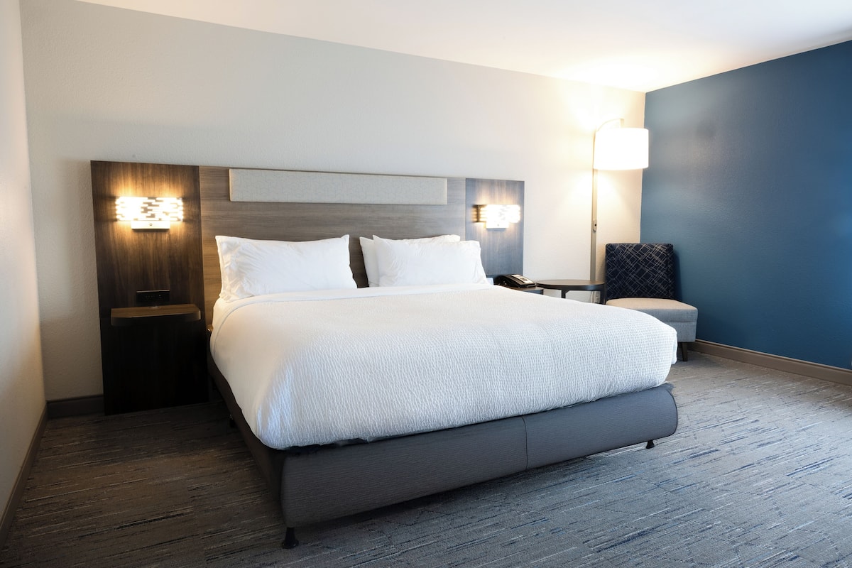Een moderne hotelkamer met een groot bed, nachtkastjes en een bijtafeltje.