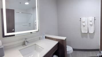 A modern bathroom with a large mirror, a sink, a toilet, and a towel rack.