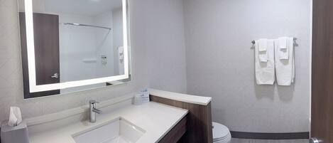 A modern bathroom with a large mirror, a sink, a toilet, and a towel rack.