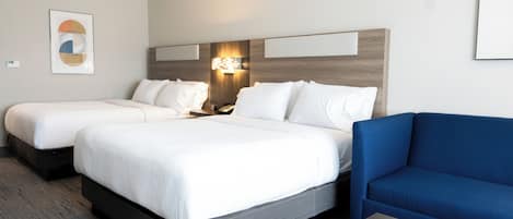A hotel room with two beds, a blue sofa, and a wooden coffee table.