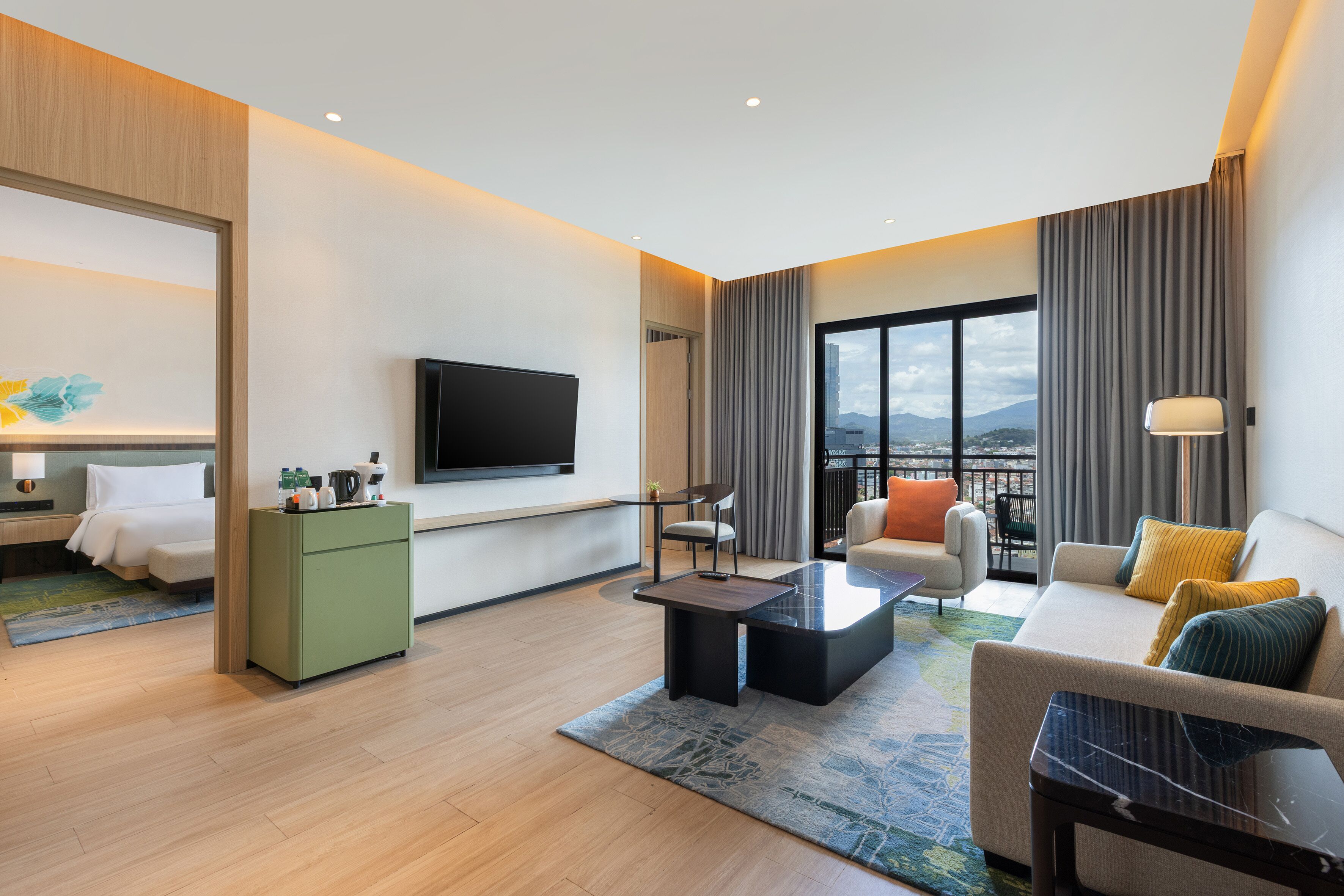 Une chambre d’hôtel moderne dotée d’une télévision à écran plat, d’un canapé, d’une table basse et d’un balcon avec vue.