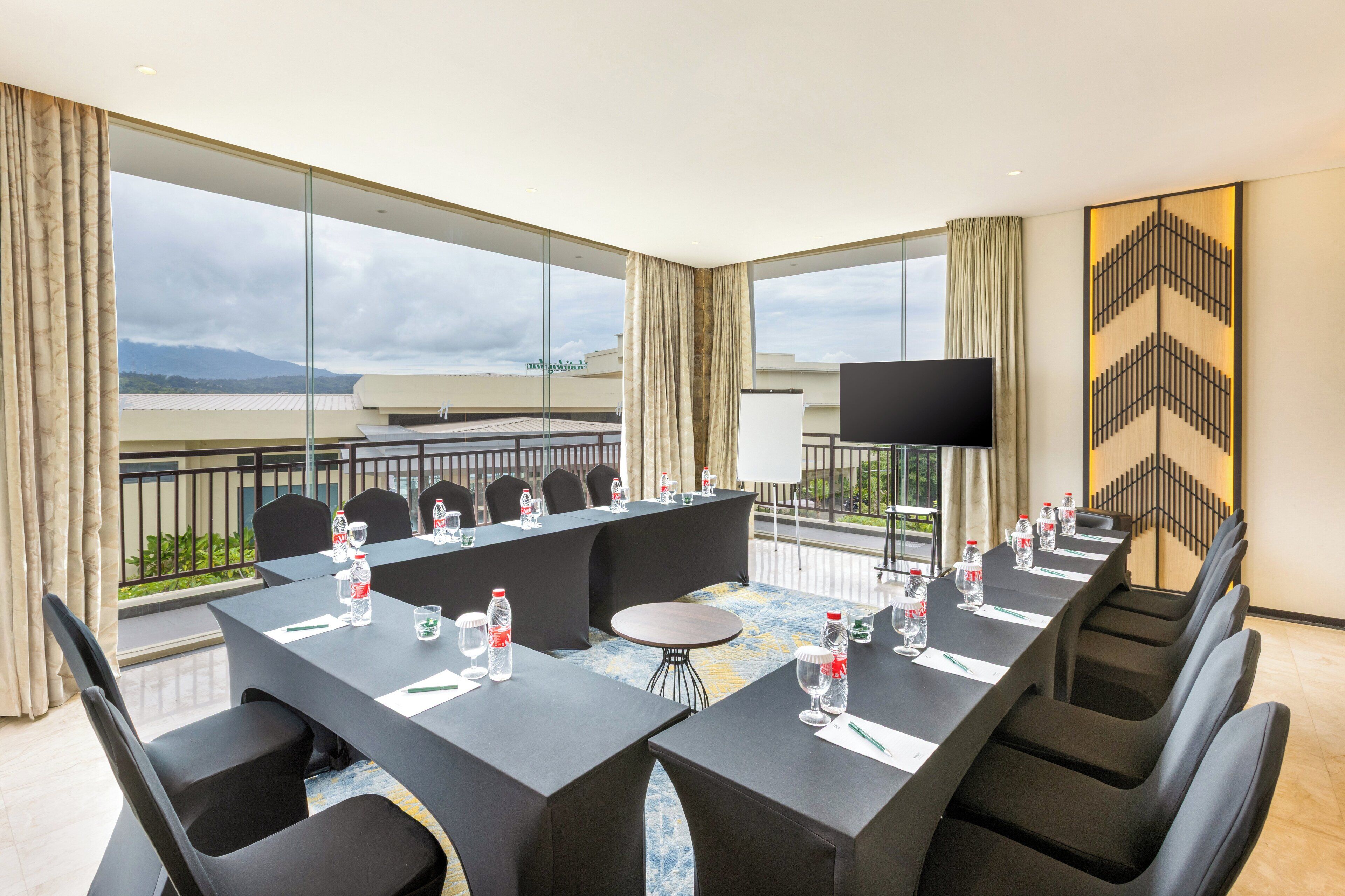 A conference room with a long table, chairs, a TV, and a view of the cityscape.