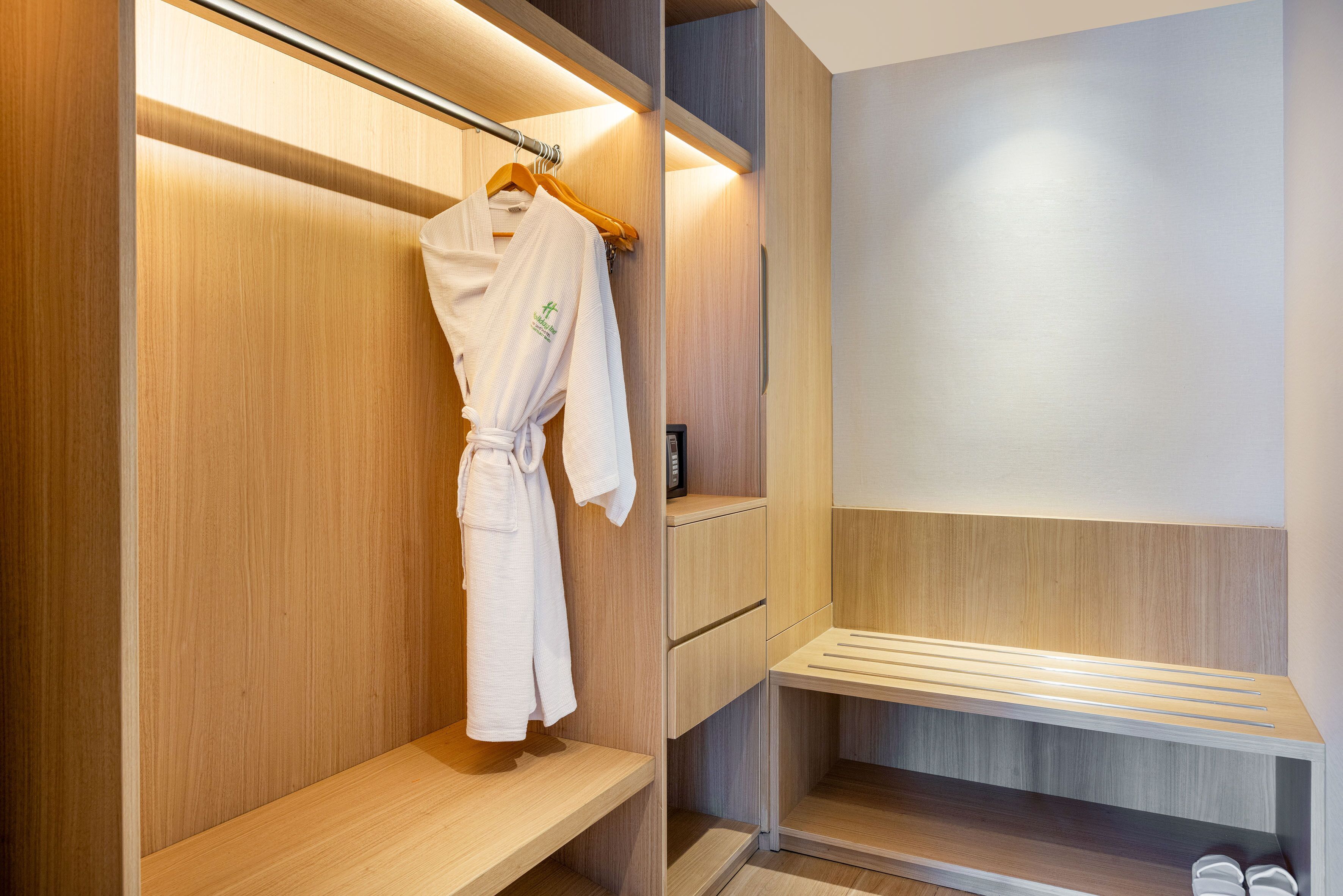 A modern bathroom with wooden cabinetry, a towel rack, and a built-in bench.