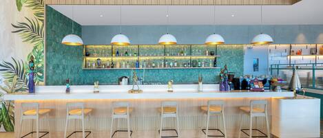 A modern bar area with a long counter, multiple hanging pendant lights, and bar stools.