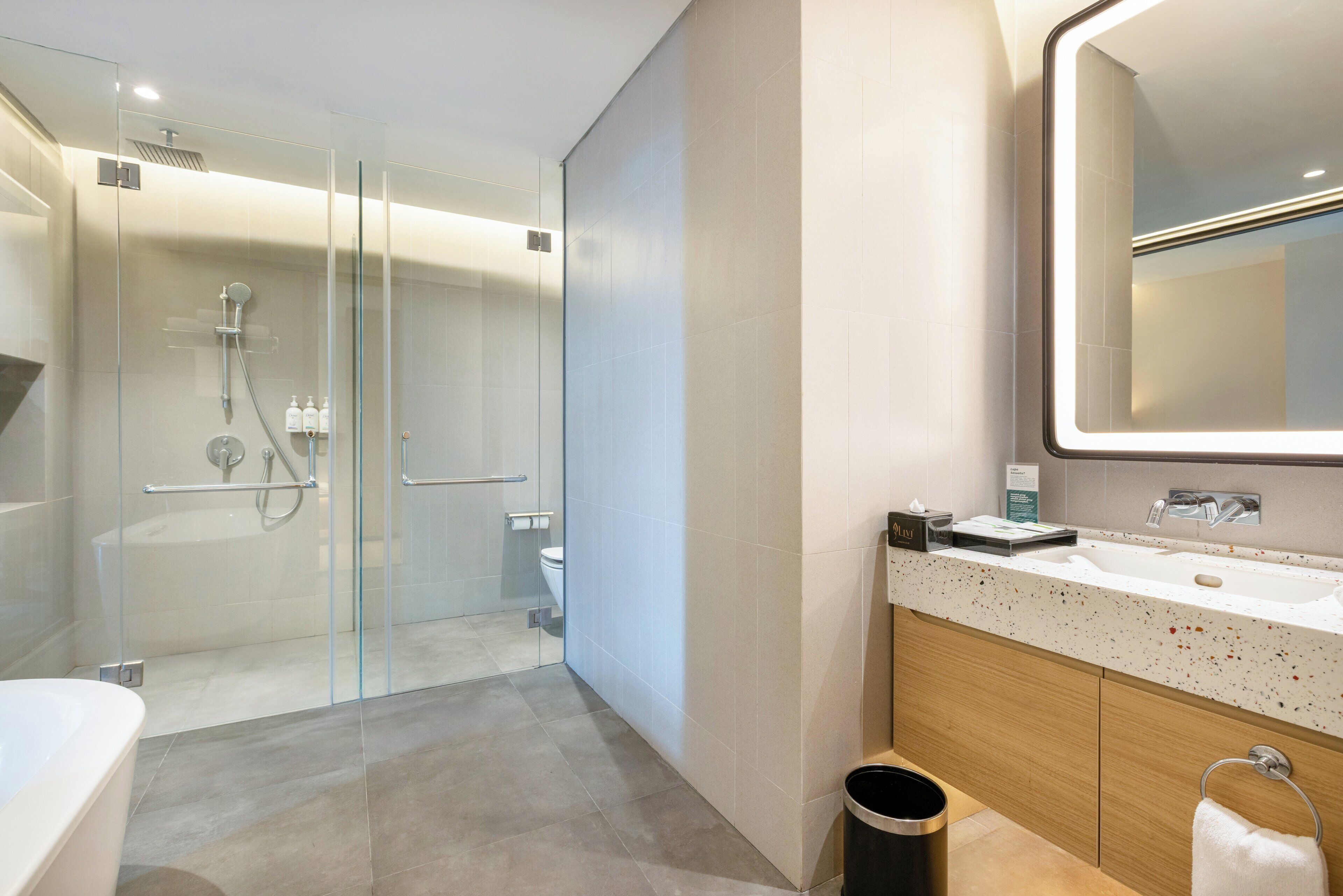 A modern bathroom with a glass-enclosed shower, a freestanding bathtub, and a vanity with a large mirror.