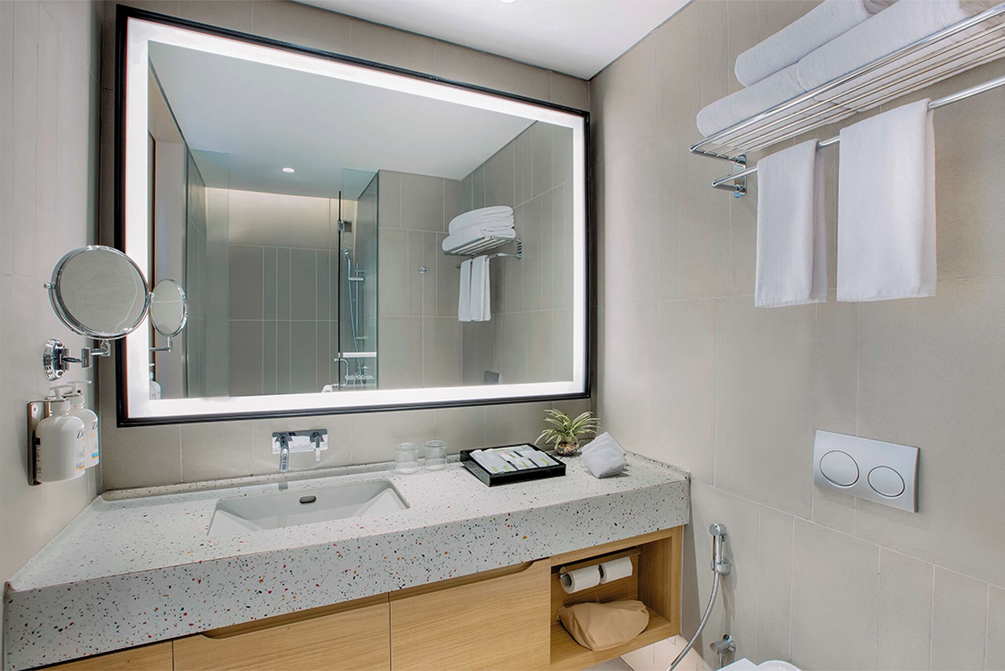 A modern bathroom with a large mirror, a sink, a towel rack, and a shower.