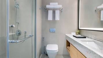 A modern bathroom with a glass shower enclosure, a toilet, a towel rack, and a sink with a mirror.