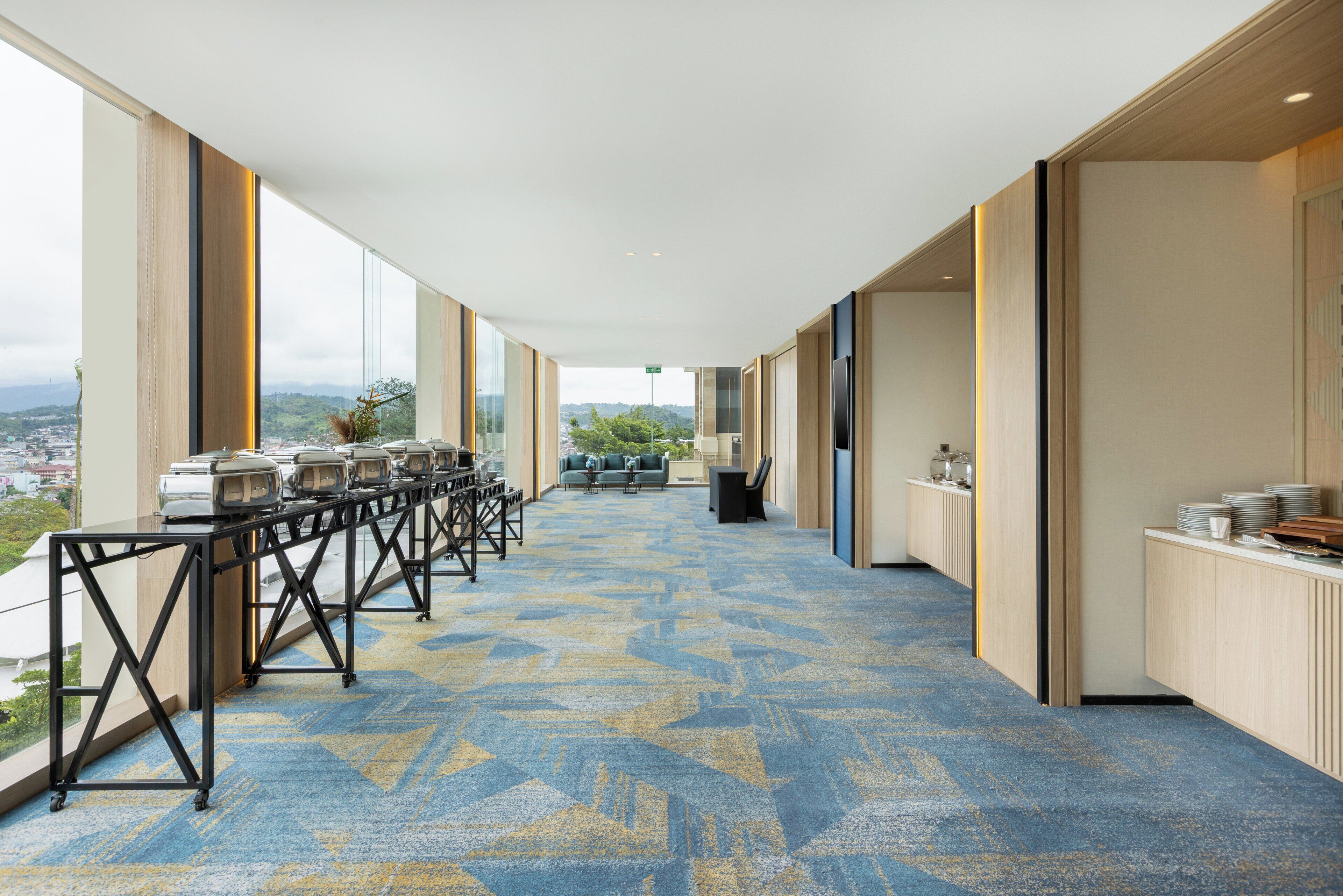 A long corridor with a patterned carpet, a reception desk, and a view of the city.