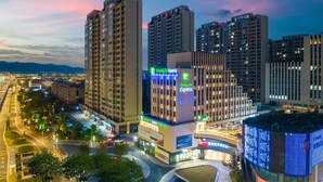 A hotel with multiple high-rise buildings, a prominent Holiday Inn Express sign, and a well-lit urban street scene. - Holiday Inn Express Suzhou Shihu University Town by IHG (Suzhou)