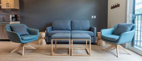 A modern living room with a grey sofa, two matching armchairs, and a wooden coffee table.