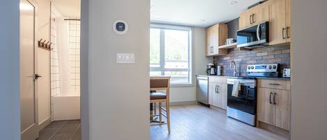 A modern kitchen with wooden cabinets, a built-in microwave, and an oven. There is a window providing natural light and a view of the outdoors.