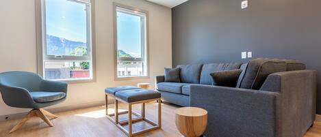 A modern living room with a grey sofa, a blue armchair, and a wooden coffee table.