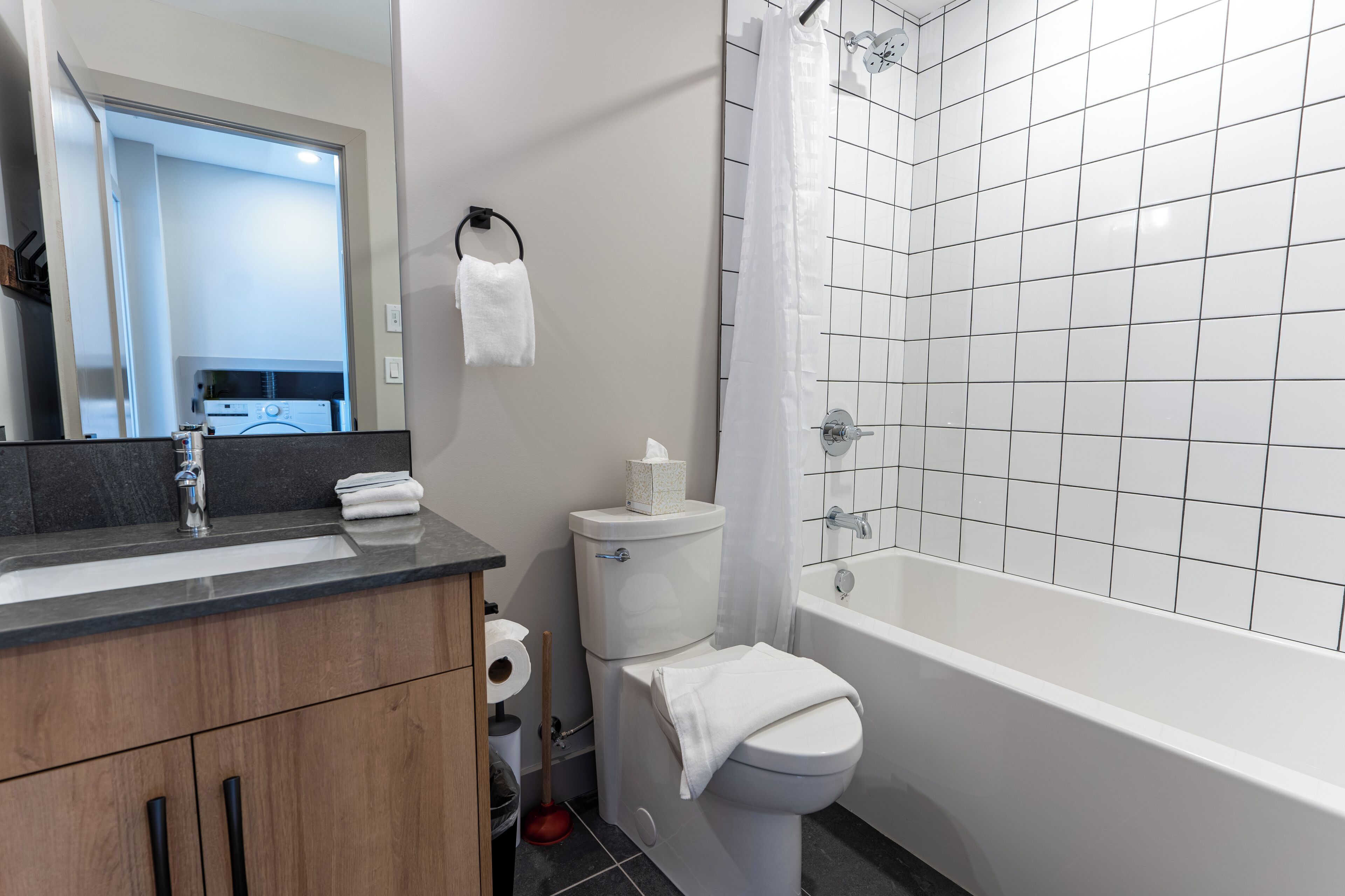 A bathroom with a white toilet, a sink with a mirror, a bathtub, and a shower curtain.