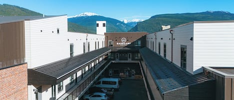 A hotel with a central courtyard, multiple parking spaces, and a mountain backdrop.