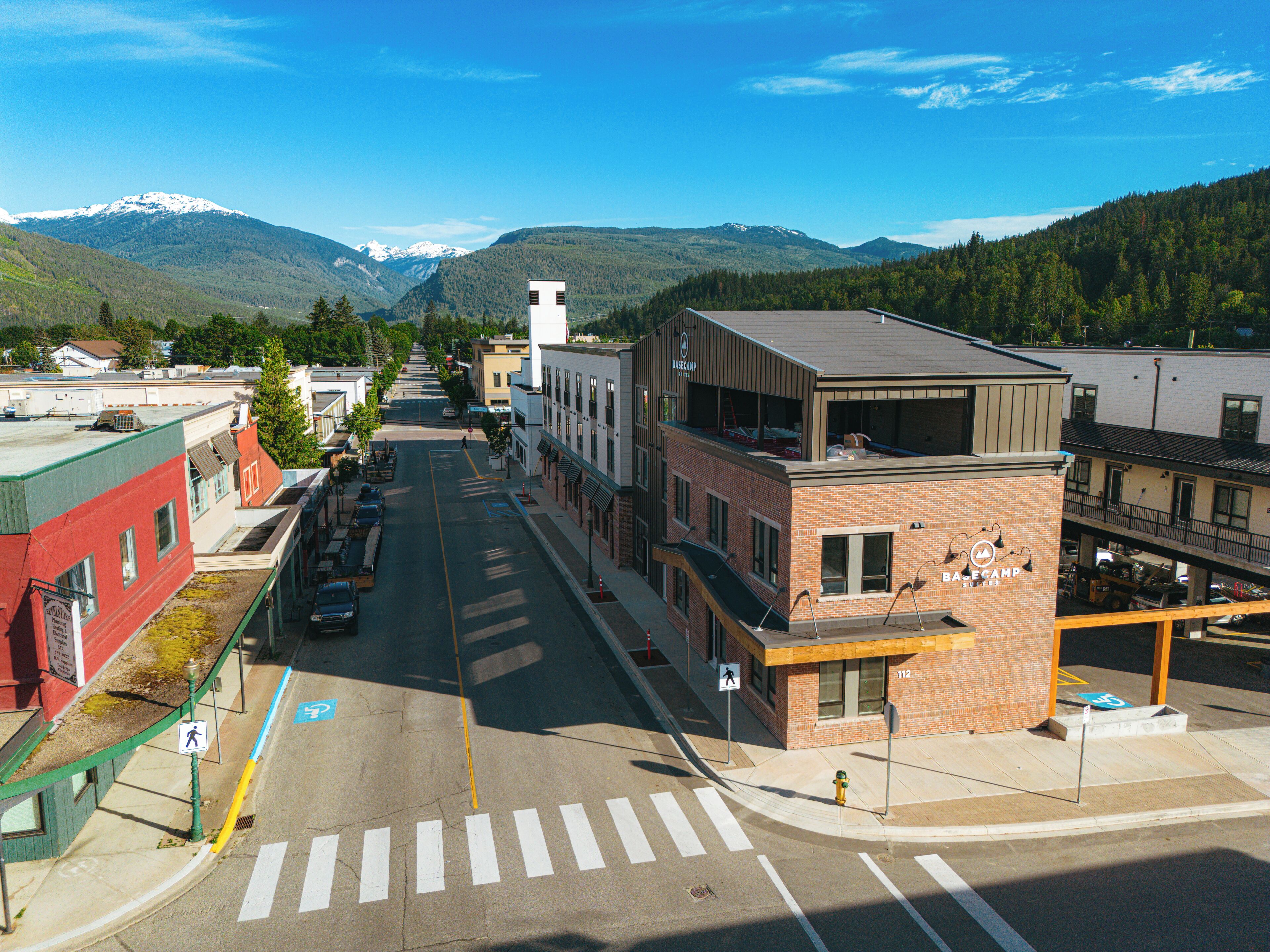 A street view with buildings, a crosswalk, and a mountain in the background.