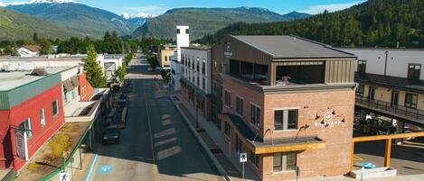 A street view with buildings, a crosswalk, and a mountain in the background.