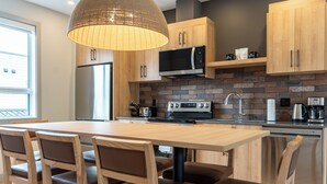 Una cocina moderna con una isla central, armarios de madera, un microondas integrado y un lavavajillas de acero inoxidable.