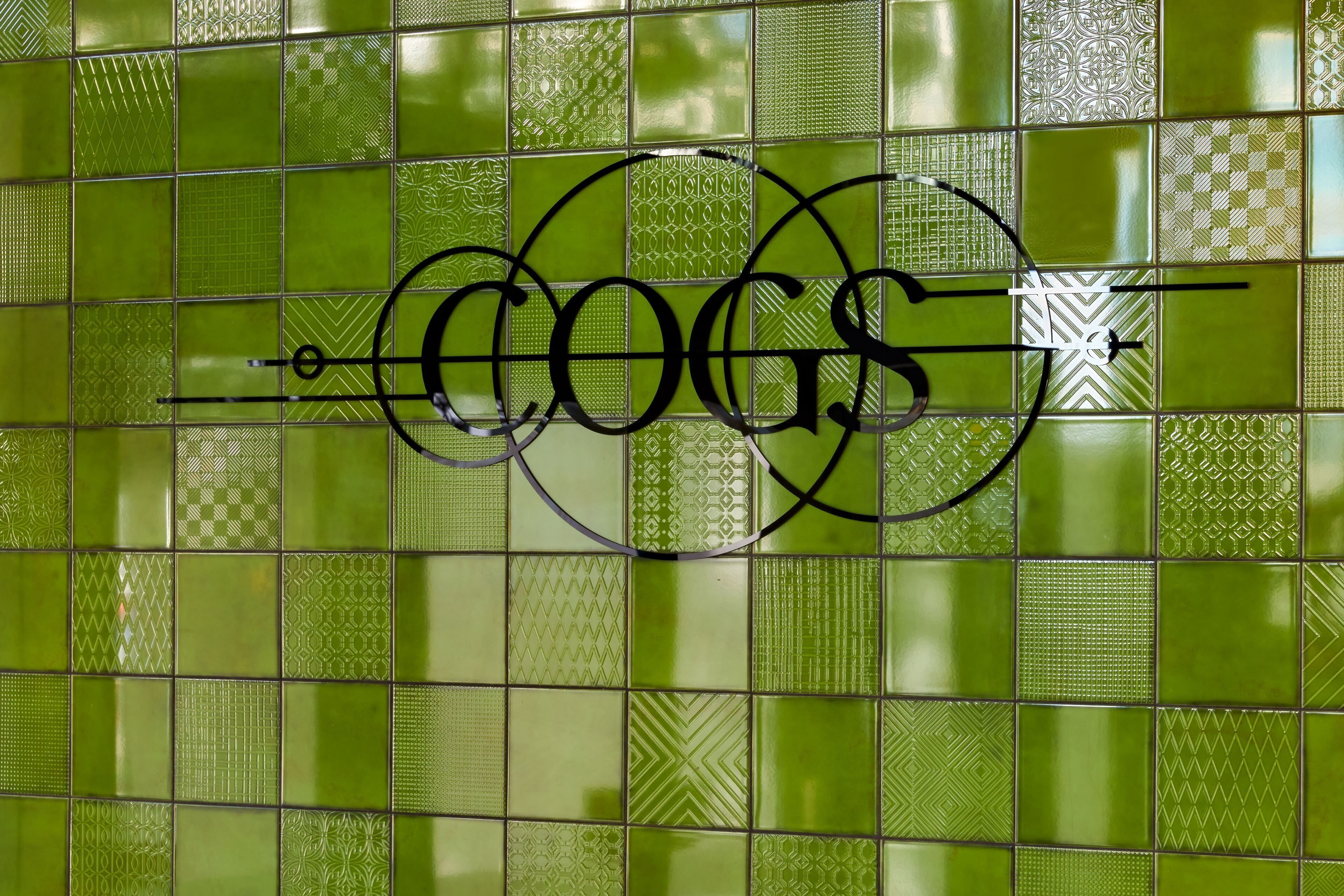 Pared verde con azulejos y un logotipo que dice "COGS".