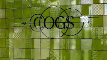 Pared verde con azulejos y un logotipo que dice "COGS".