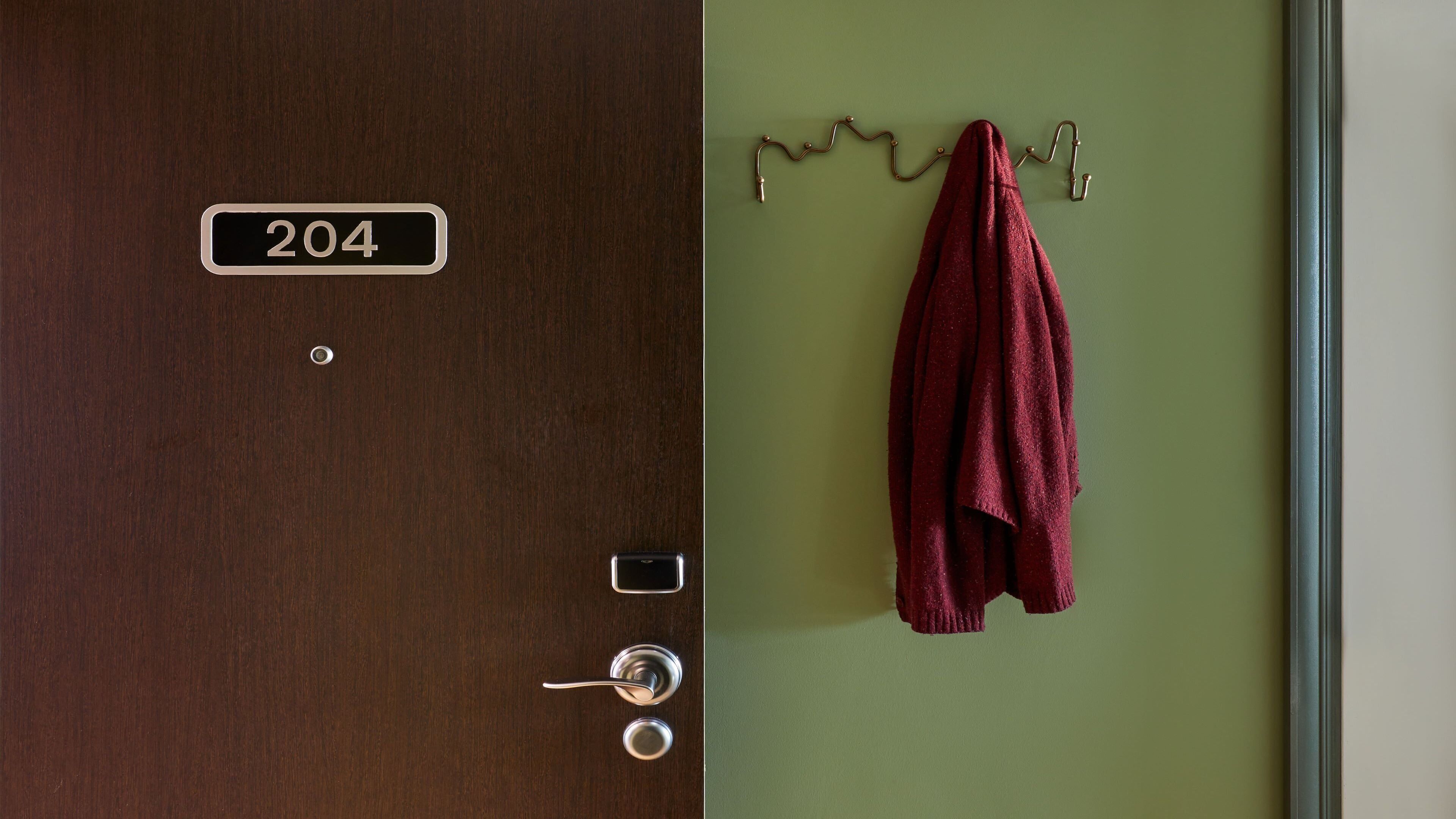 A hotel room door with a number plate, a keyhole, and a towel hanging on a hook.