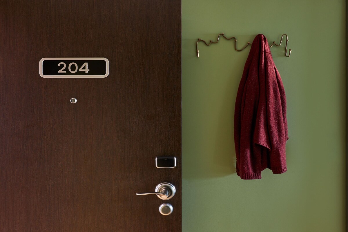 A hotel room door with a number plate '204', a keyhole, a door handle, and a towel hanging on a hook.