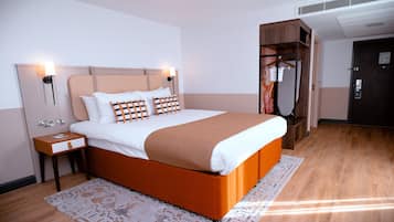 A modern hotel room with a large bed, bedside tables, a wardrobe, and a mirror.